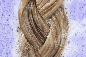Blonde hair being washed in purple shampoo